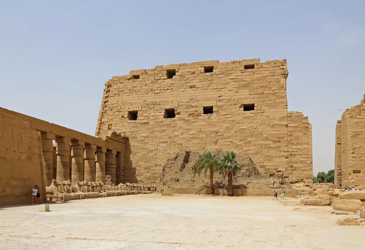 Great Forecourt of Karnak Temple with a massive pylon and a palm tree