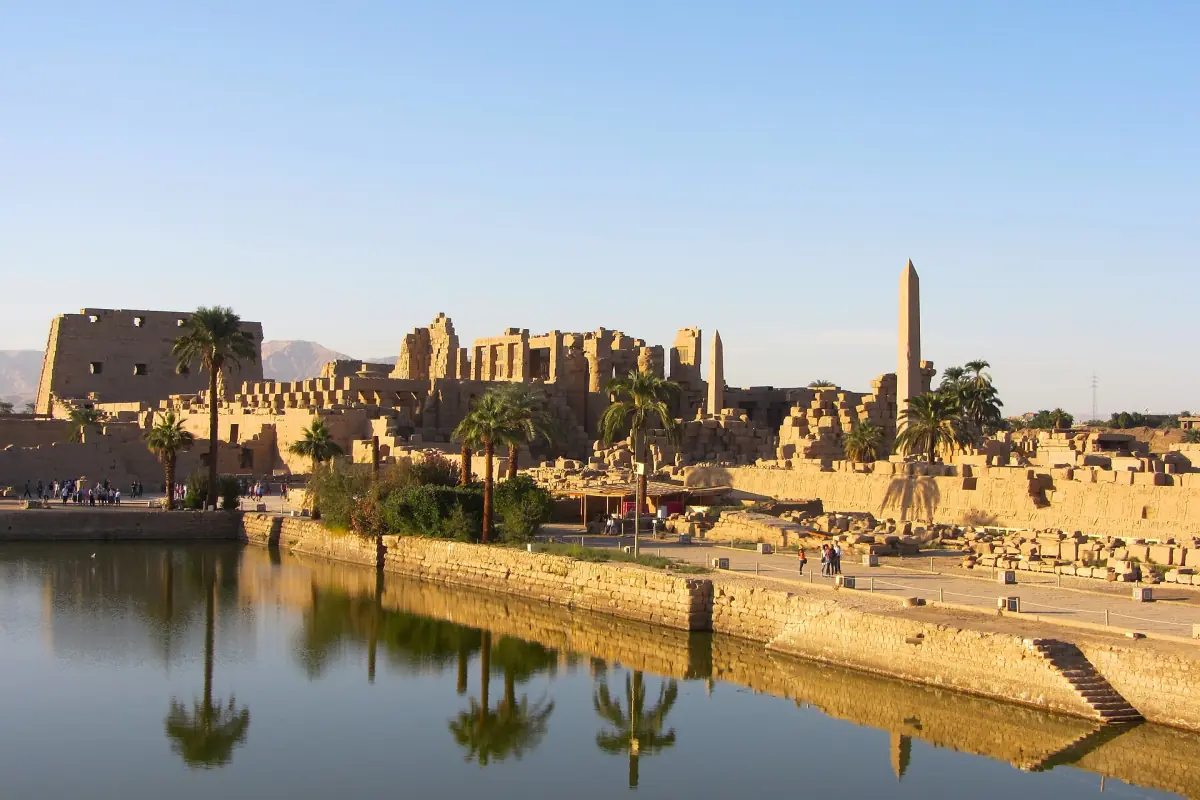 Karnak temple complex and an obelisk reflected in the lake in golden light