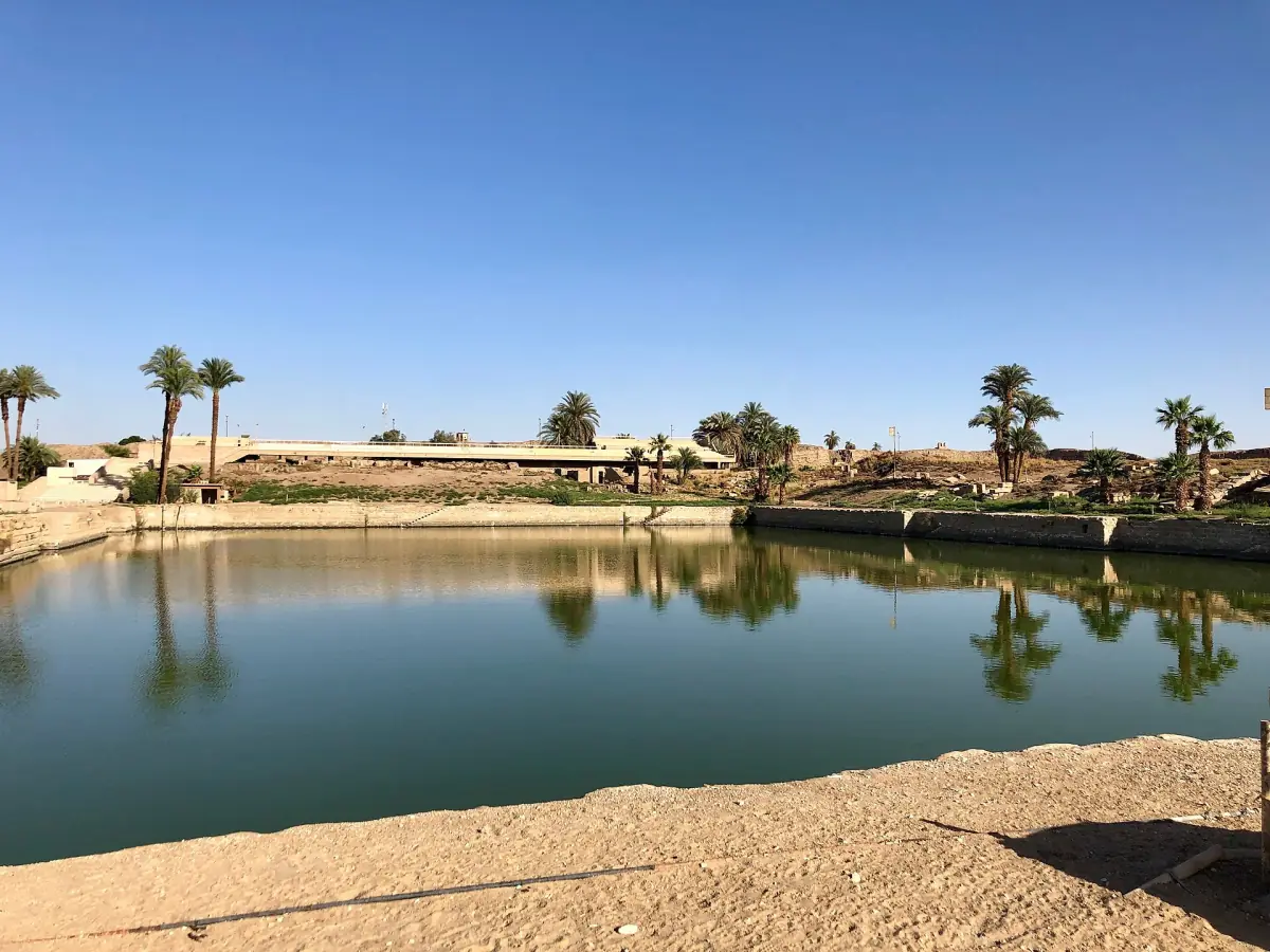 Sacred Lake at Karnak with palm trees along the sandy shore