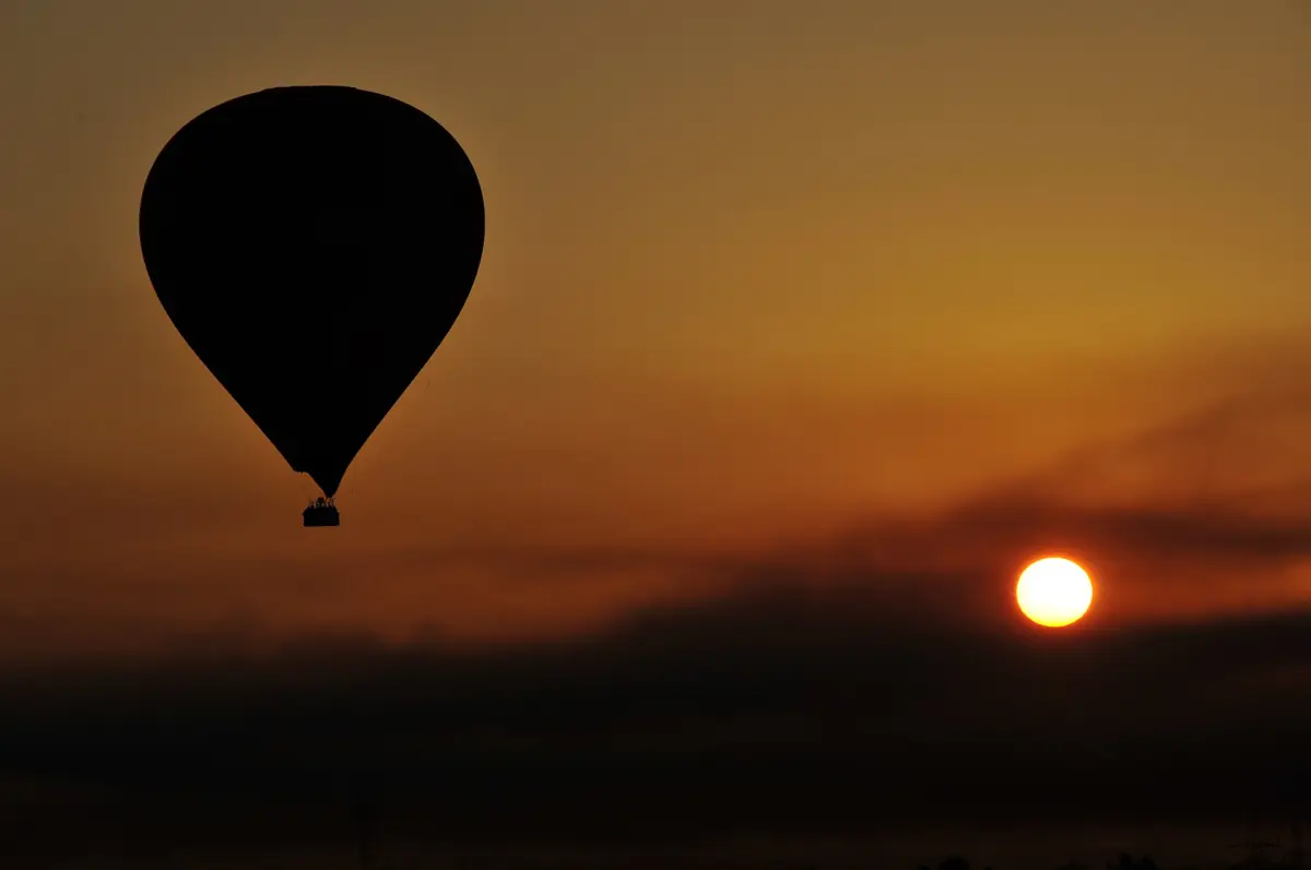Hot air balloon silhouetted against the rising sun over Luxor