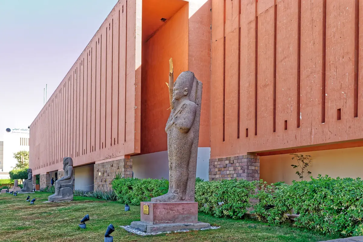 Luxor Museum red facade with a pharaoh statue standing in the garden