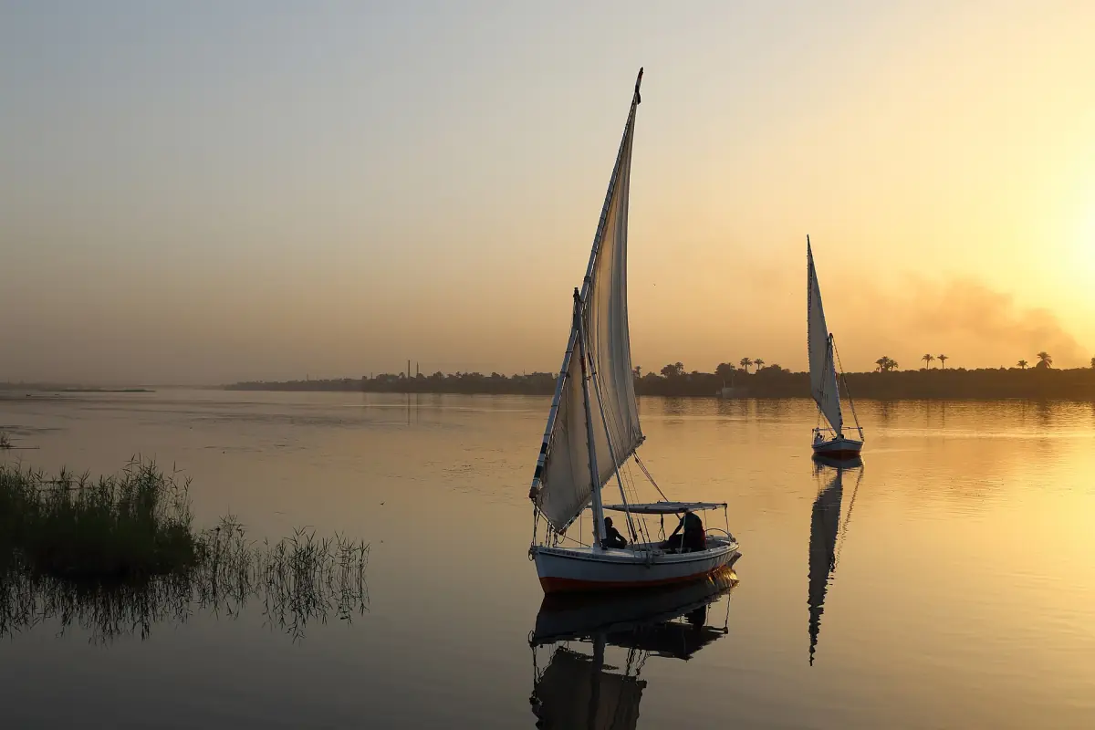 Felucca sailing on calm golden Nile water near Luxor