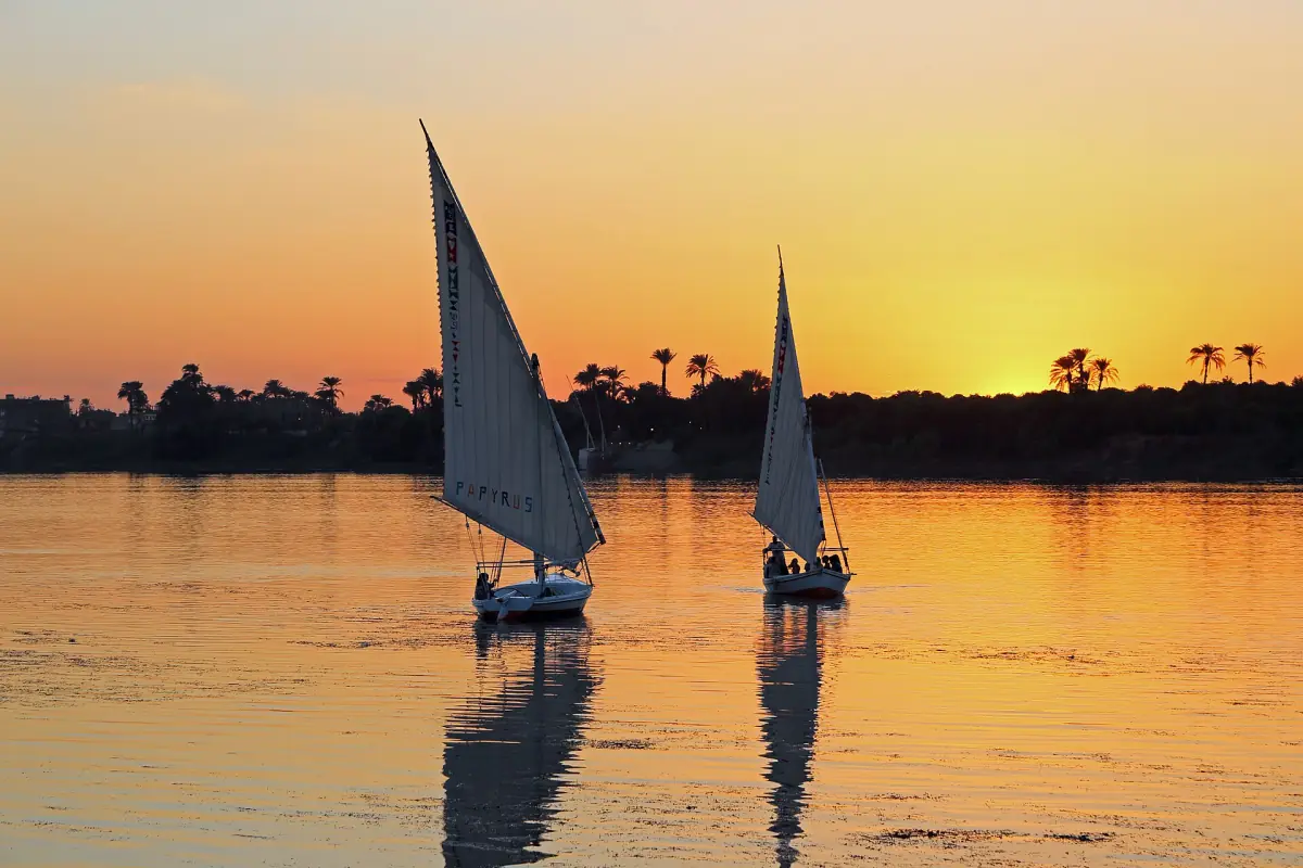 Two feluccas with white sails on the Nile at sunset in Luxor