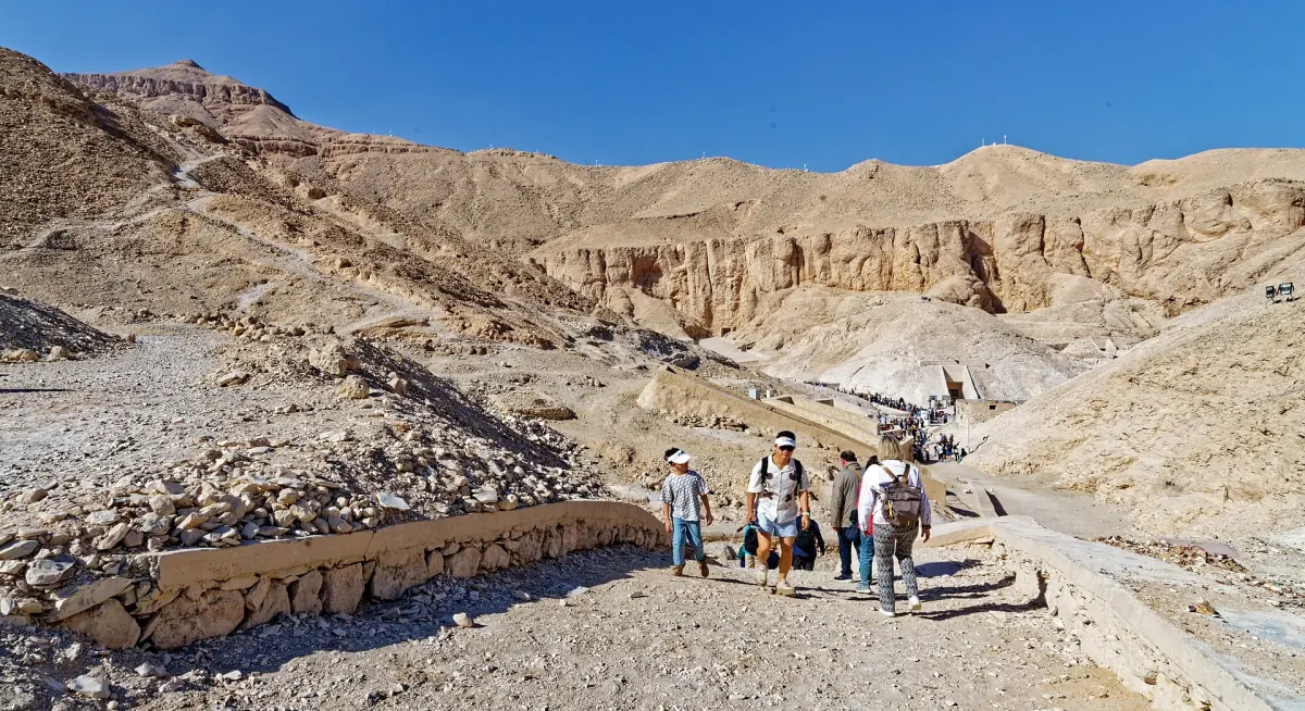 Rocky desert valley of the Valley of the Kings with visitors on the path